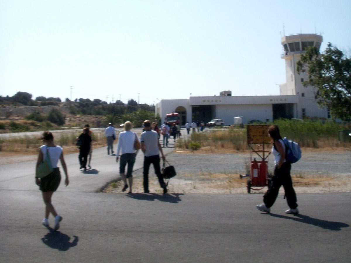 Αεροδρόμιο Μήλου: ο μικρός αεροσταθμός με τον πύργο ελέγχου και επιβάτες που περπατούν προς την είσοδο
