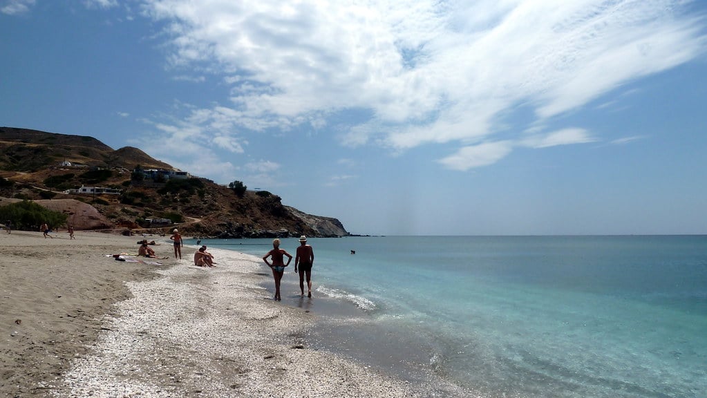 Αγία Κυριακή παραλία Μήλος: ανοιχτόχρωμη ακτή με λεπτό βότσαλο, λουόμενοι και καθαρά νερά