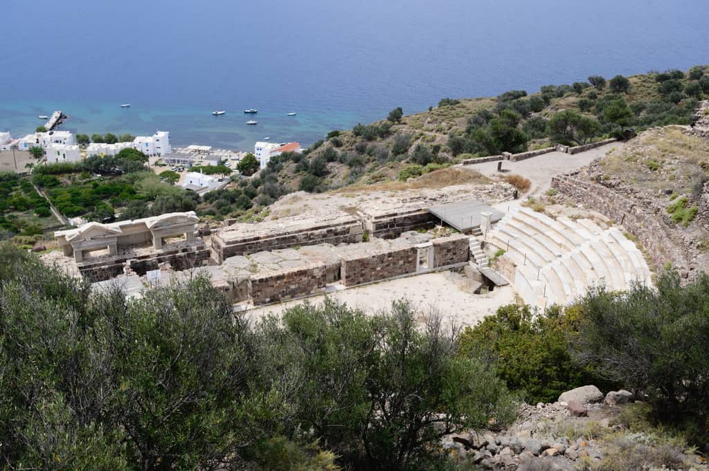 Αρχαίο θέατρο Μήλου: τα μαρμάρινα καθίσματα και η σκηνή στην πλαγιά, με το Κλήμα και τον κόλπο από κάτω