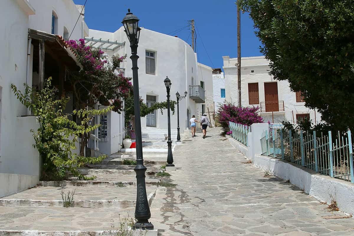 Accommodation in Milos: a paved lane with white houses, bougainvillea and street lamps in Plaka