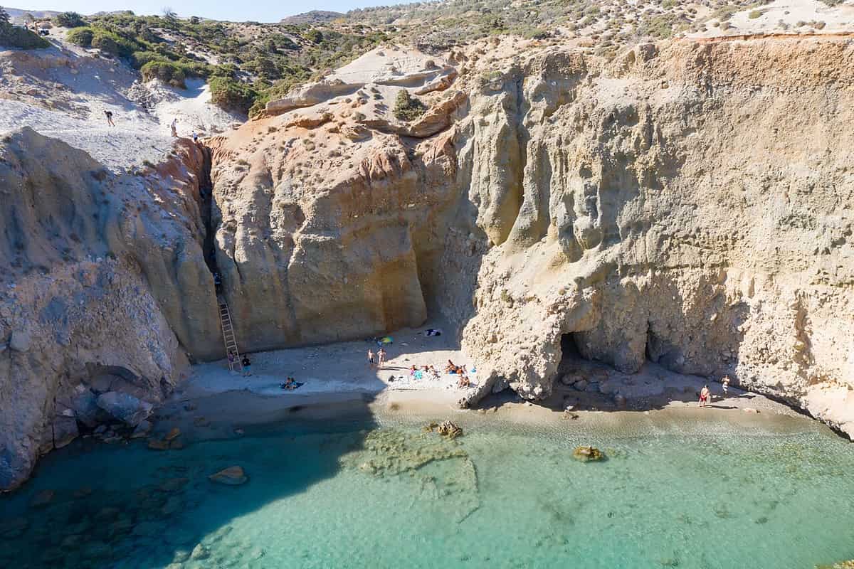 Beaches of Milos: Tsigrado, a small sandy cove between tall cliffs, reached by a wooden ladder