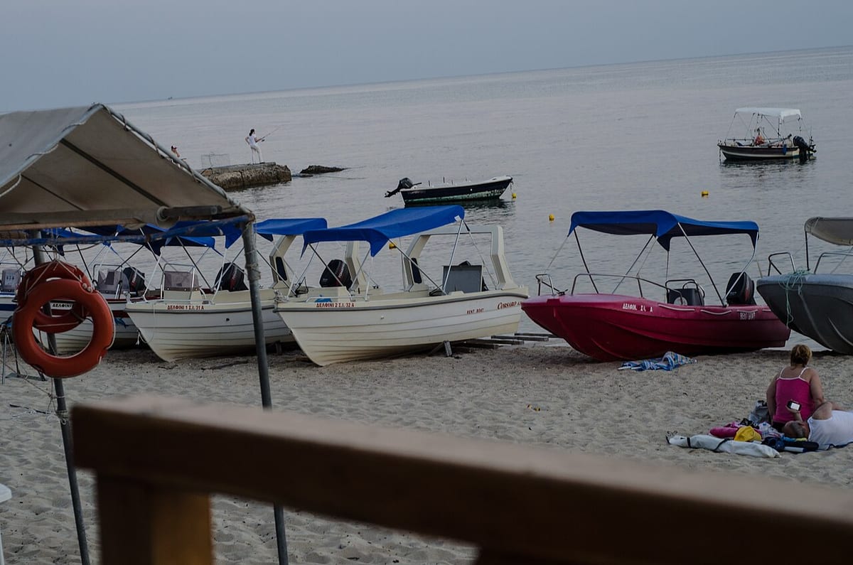 Milos boat rental: small motorboats with blue canopies pulled up on a sandy beach, ready for the day