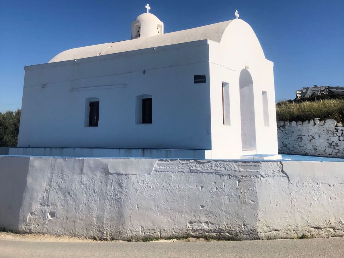 Coffee and drinks in Triovasalos: a whitewashed chapel with a small dome and bell tower beside the road in Triovasalos, Milos