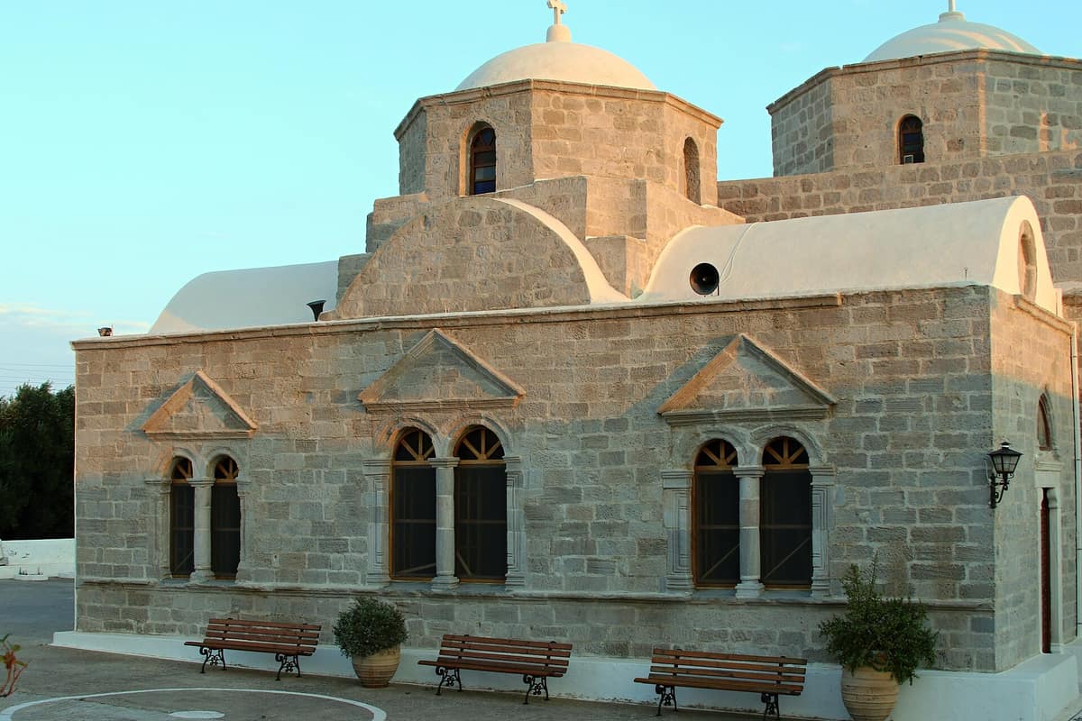 Coffee and drinks in Zefiria: the stone church of Panagia Portiani with its domes and arched windows, with benches on the paved forecourt