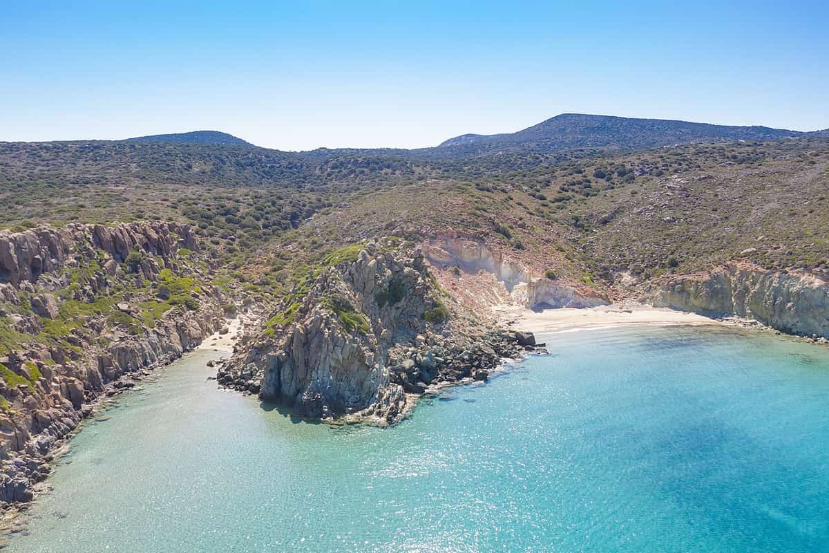 Combined activities in Milos: a secluded cove with turquoise water below green hills and rocky headlands in the south-west