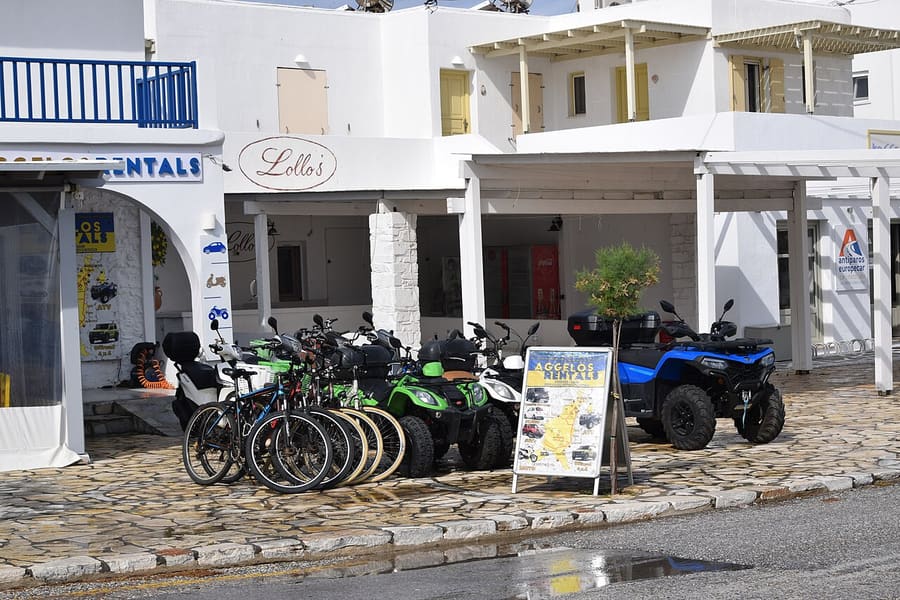 Milos e-bike tour: a row of bicycles and quad bikes lined up for hire outside white Cycladic buildings