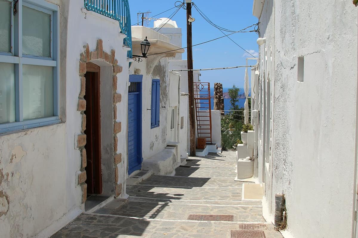 Food in Plaka Milos: a paved lane between whitewashed houses with blue doors and windows in Plaka, the capital of Milos