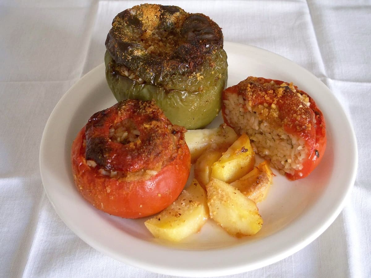 Food in Zefiria: gemista, tomatoes and a green pepper stuffed with rice and baked with potatoes, on a white plate