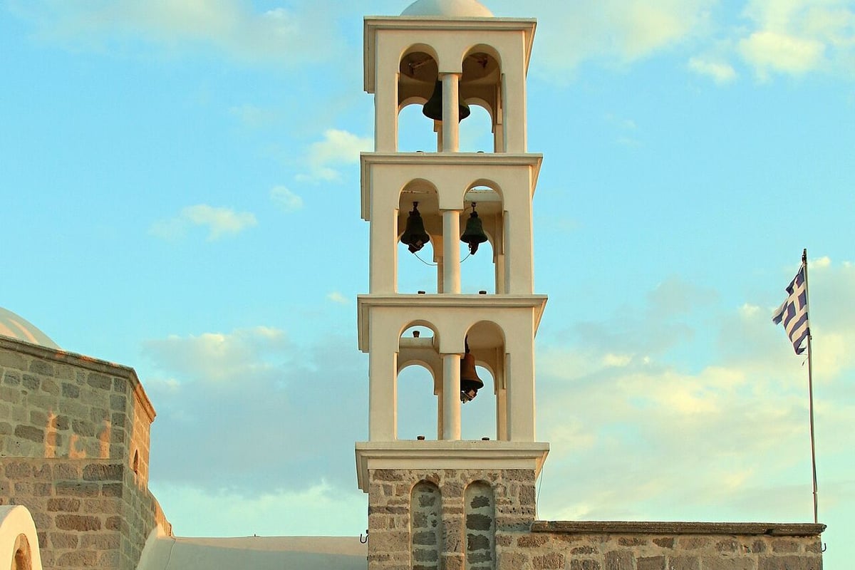 Food in Zefiria: the tall white bell tower of Panagia Portiani rising above the stone church in Zefiria, Milos