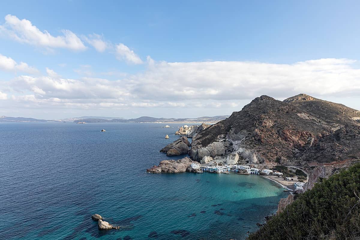 Fyropotamos: the boathouses and beach at the head of a turquoise bay below a rocky hill on the north coast of Milos
