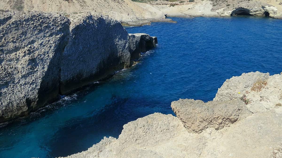 Hiking in Milos: pale volcanic rock along the coast path from Phylakopi towards Papafragas, above deep blue water