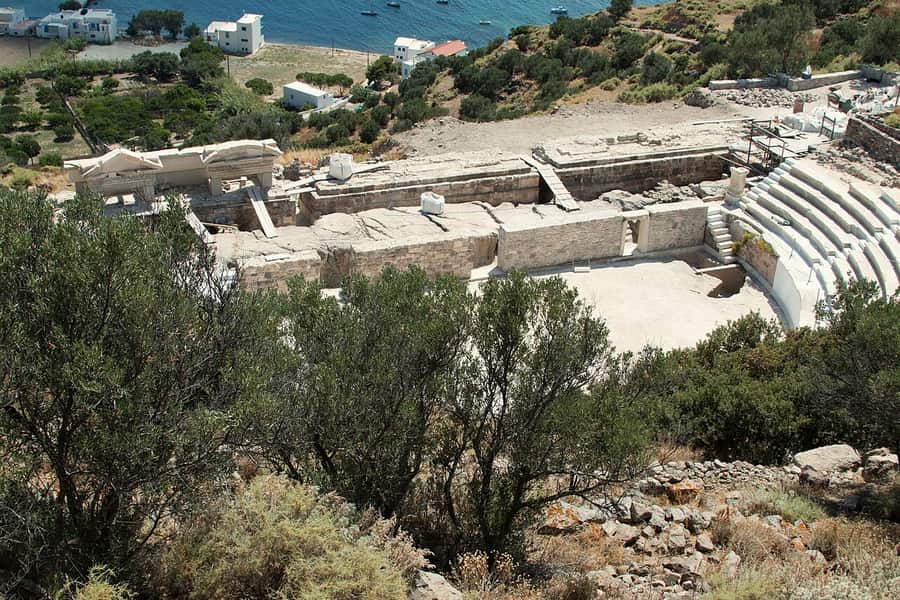 Milos island tour: the marble seats of the ancient theatre of Milos among olive trees, with the bay below