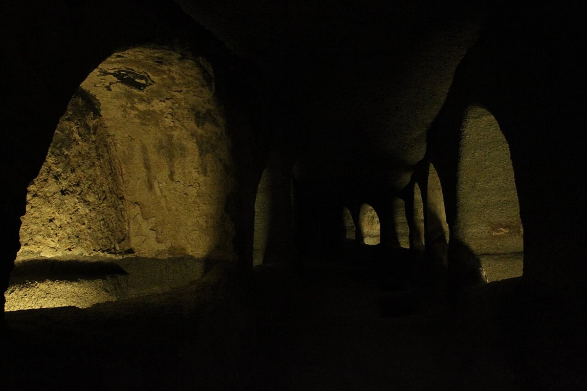 Milos island tour: a softly lit underground gallery of the Christian catacombs of Milos with arched tomb niches
