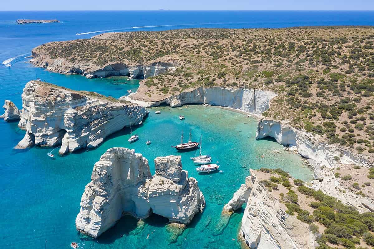 Milos itinerary: white cliffs, rock pillars and anchored boats in the turquoise bay of Kleftiko