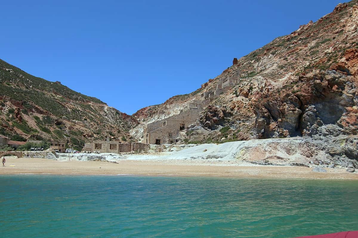 Kayak Thiorichia: the ruined buildings of the abandoned sulphur mines above the sandy cove of Thiorichia, under red and grey cliffs on the east coast of Milos