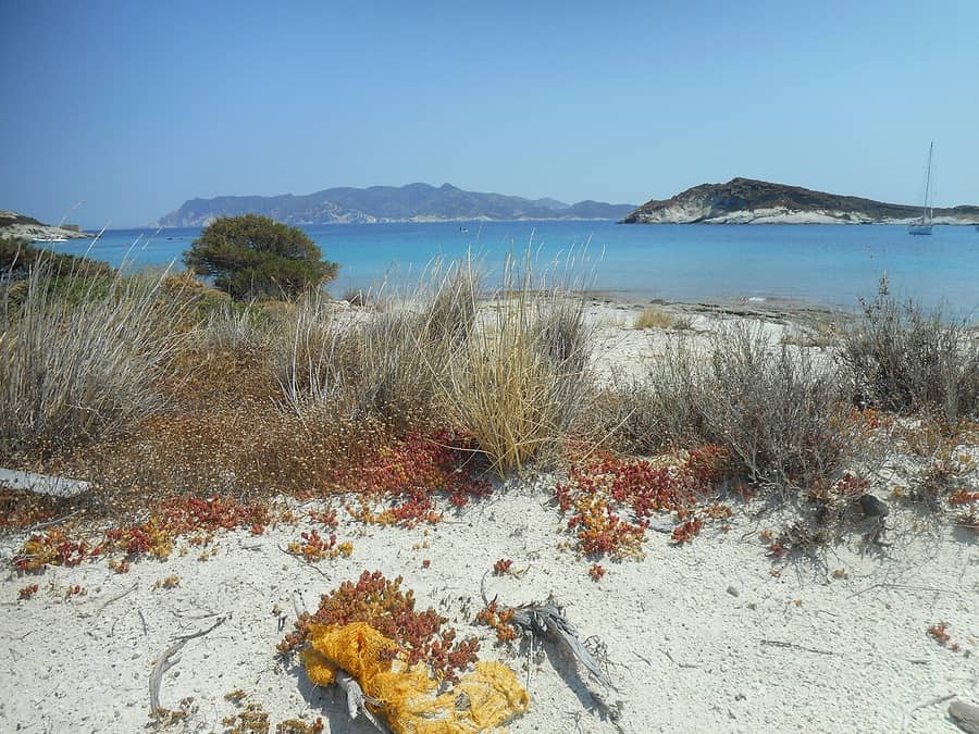 Kimolos boat trip: the pale sand and clear blue water of Prassa beach on Kimolos, with low islets across the strait