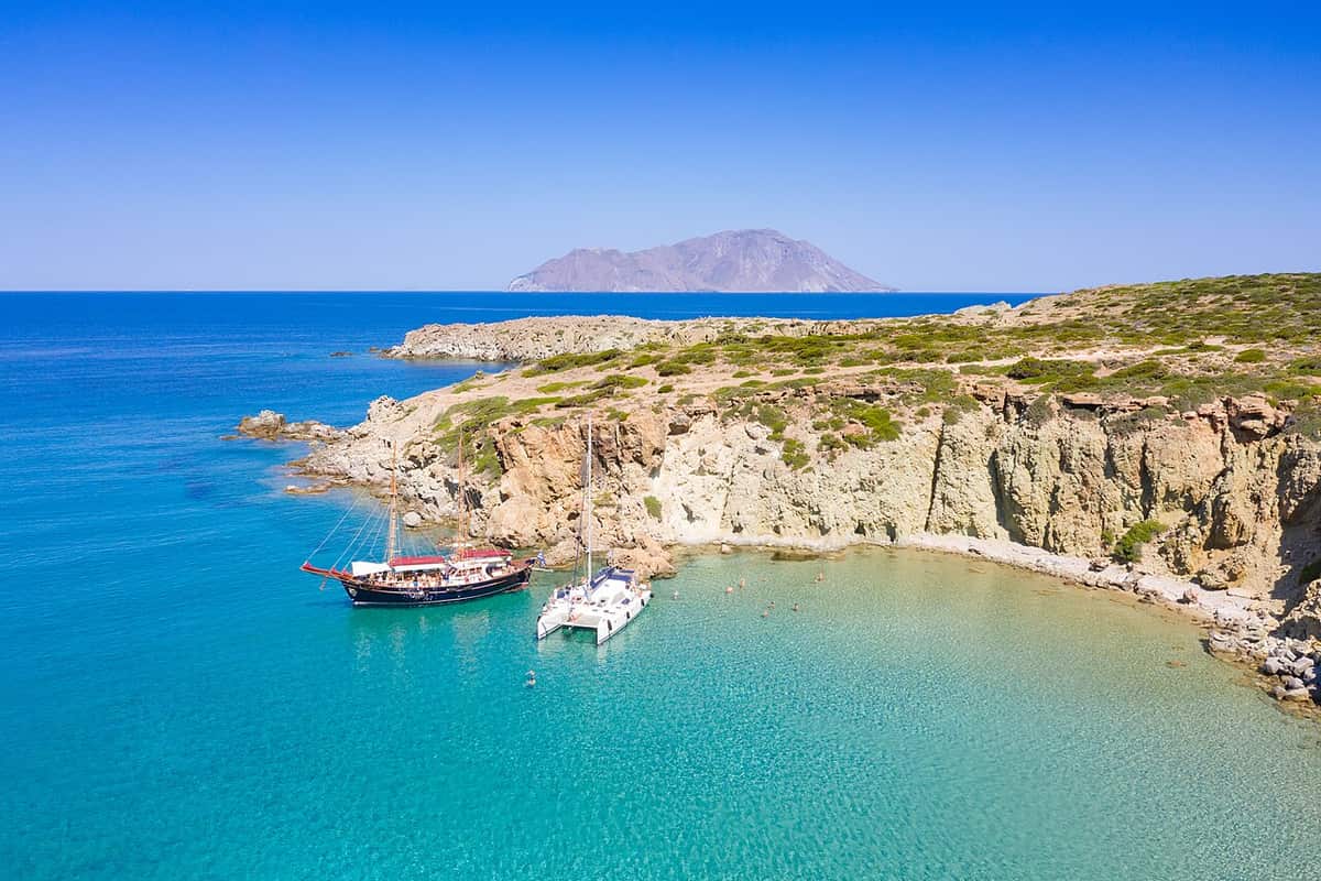 Kleftiko boat tour: a catamaran and a wooden two-masted boat at anchor in a turquoise cove at Kleftiko