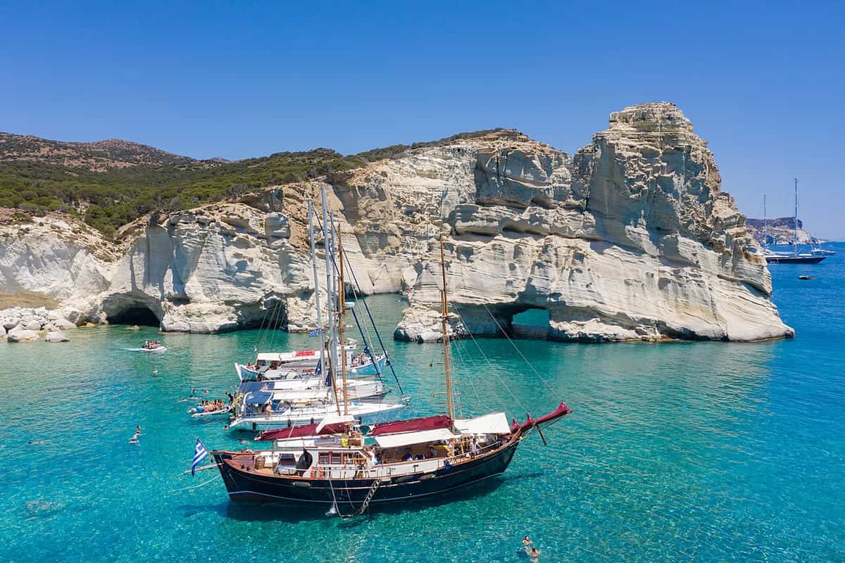 Kleftiko hike Milos: the white rock arches and sea caves of Kleftiko above turquoise water, with sailing boats at anchor