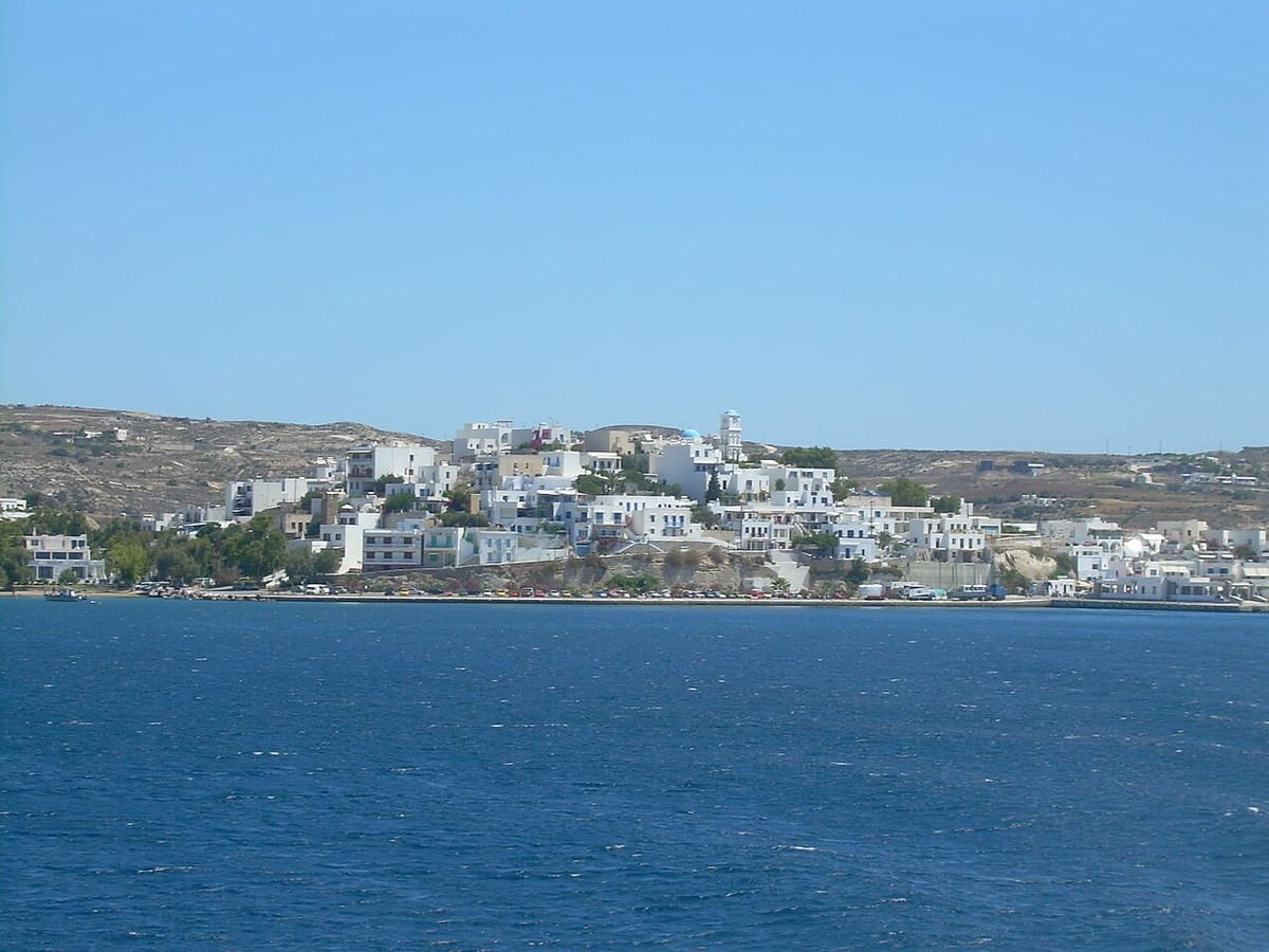 Miland Suites Milos: the white houses of Adamas along the shore of the gulf of Milos, seen from the sea