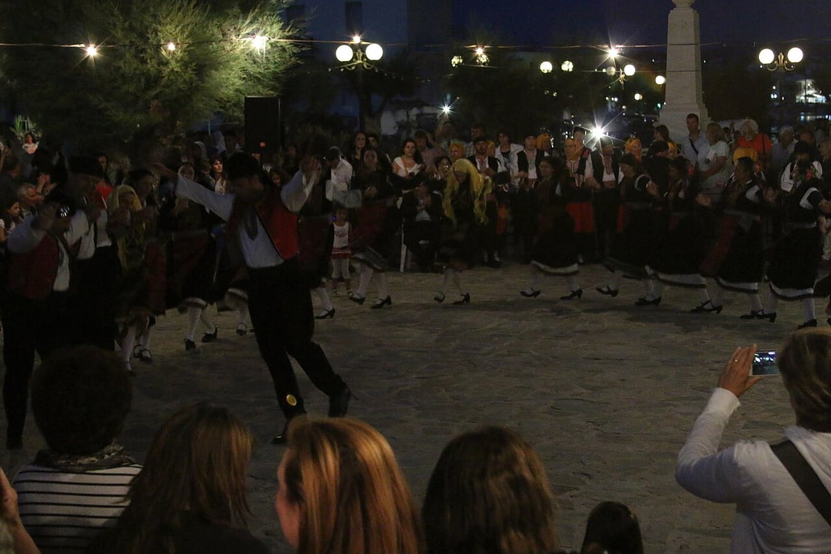 Milos nightlife: dancers in traditional costume dance in a lit square in Adamas while a crowd watches