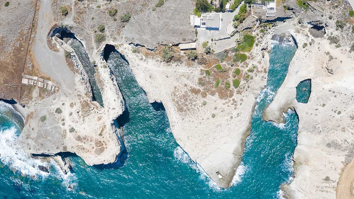 Papafragas: aerial view of the white rock coast with deep turquoise inlets cutting into the cliffs