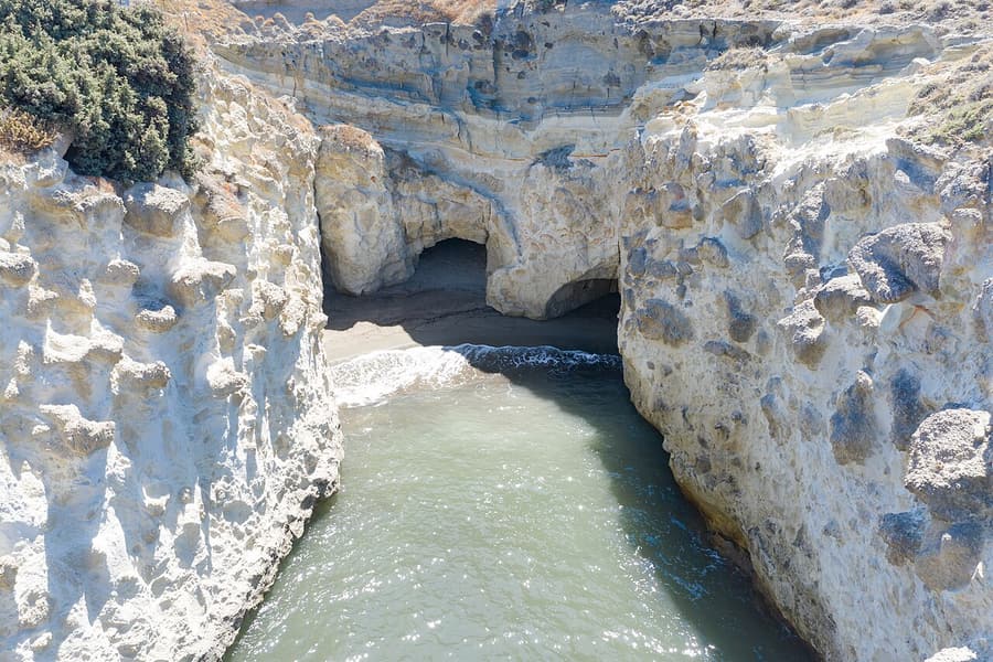 Papafragas: a narrow sea inlet between pale volcanic cliffs, with a small sandy cove under a cave arch