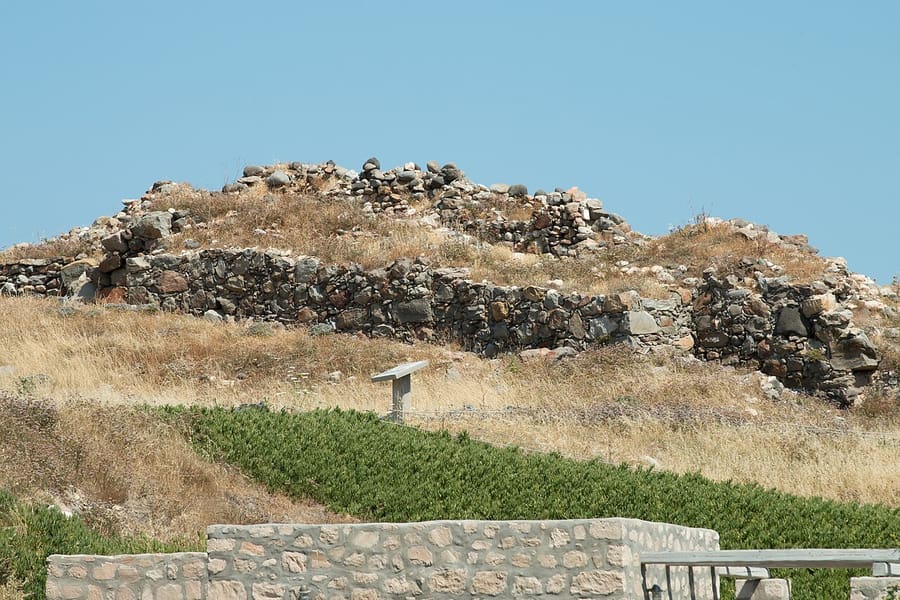 Phylakopi: the stone walls of the Bronze Age town on a low hill on the north coast of Milos, with an information sign