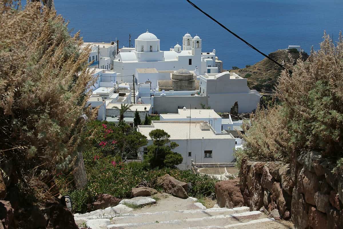 Plaka Milos: a stone path down from the Kastro to the white church of Panagia Korfiatissa with its dome and bell towers above the sea