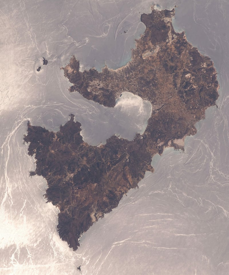 Rent a car Milos: the whole island of Milos seen from space, with the horseshoe gulf in the middle and the hills of the west