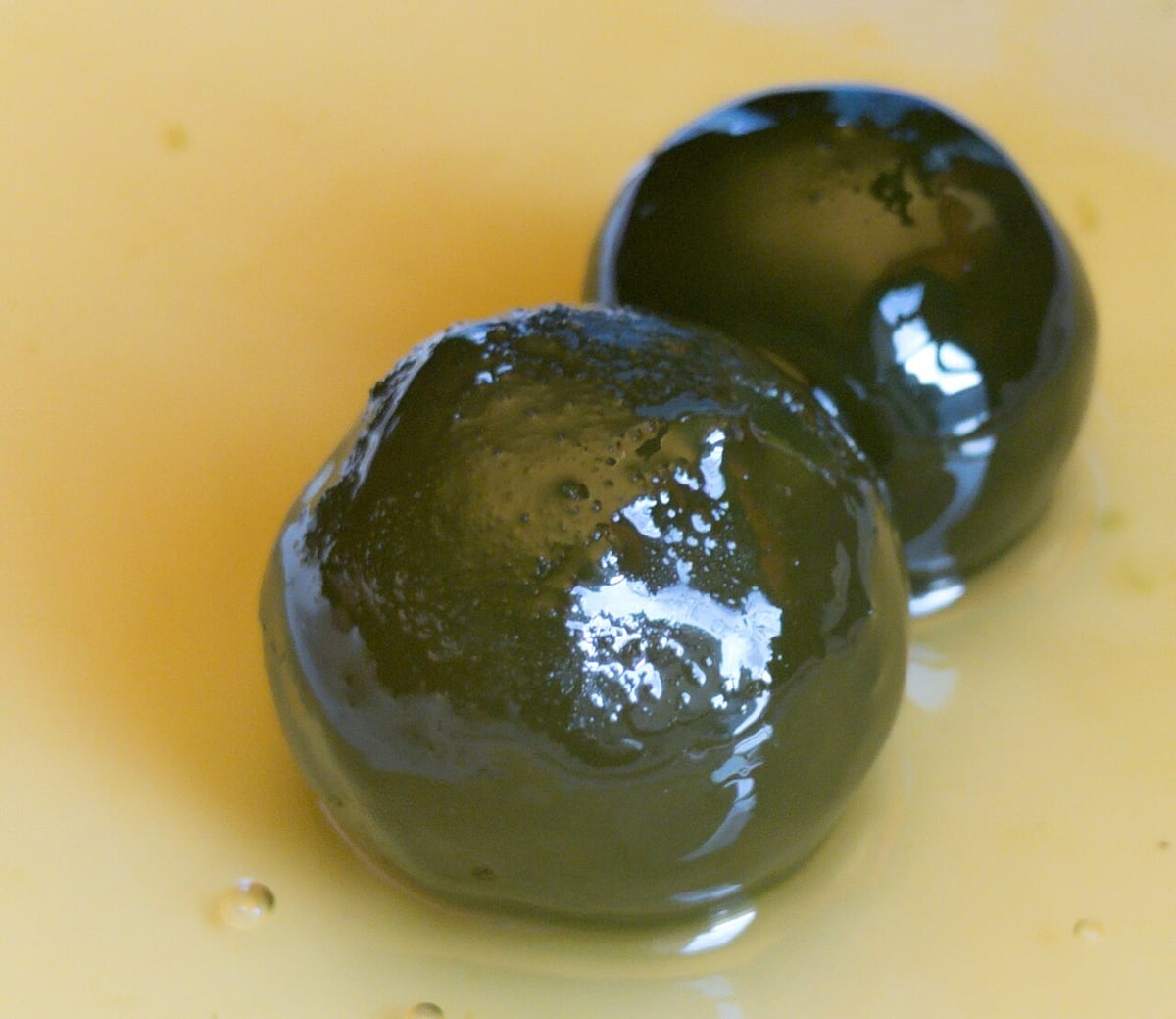 Sweets in Milos: two glossy candied green oranges in syrup, a traditional Greek spoon sweet