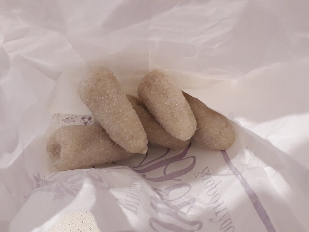 Sweets in Tripiti: amygdalota, white almond sweets of the Cyclades dusted with sugar, on a paper wrapper