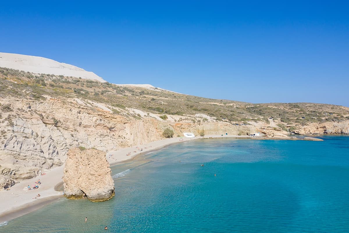 Tsigrado beach: the long curve of Firiplaka beach next door, with a rock pillar in clear turquoise water