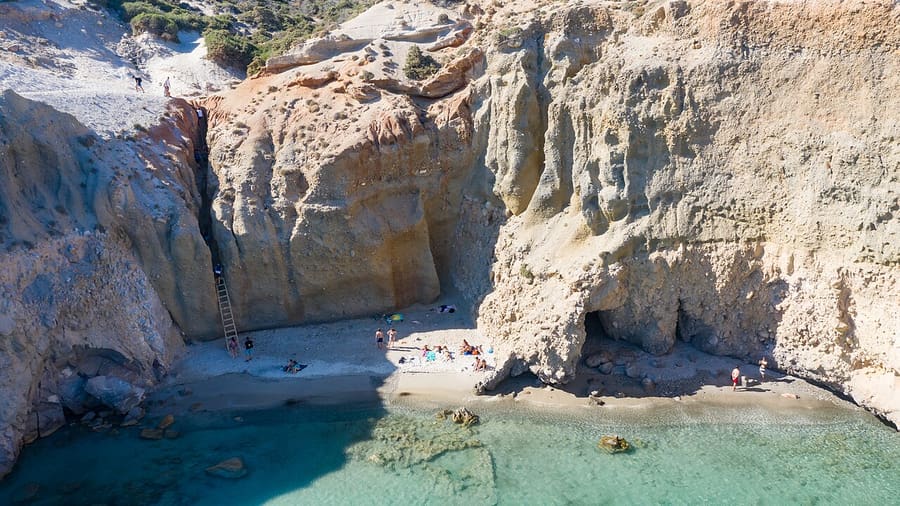 Tsigrado beach: a wooden ladder fixed in a narrow gap of the tall pale cliffs above the small sandy cove