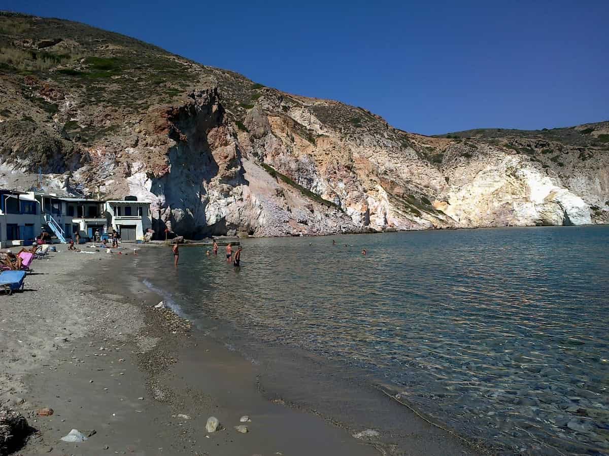 Φυροπόταμος Μήλος: η αμμουδιά του κόλπου με τα σύρματα και τους ανοιχτόχρωμους ηφαιστειακούς βράχους από πάνω