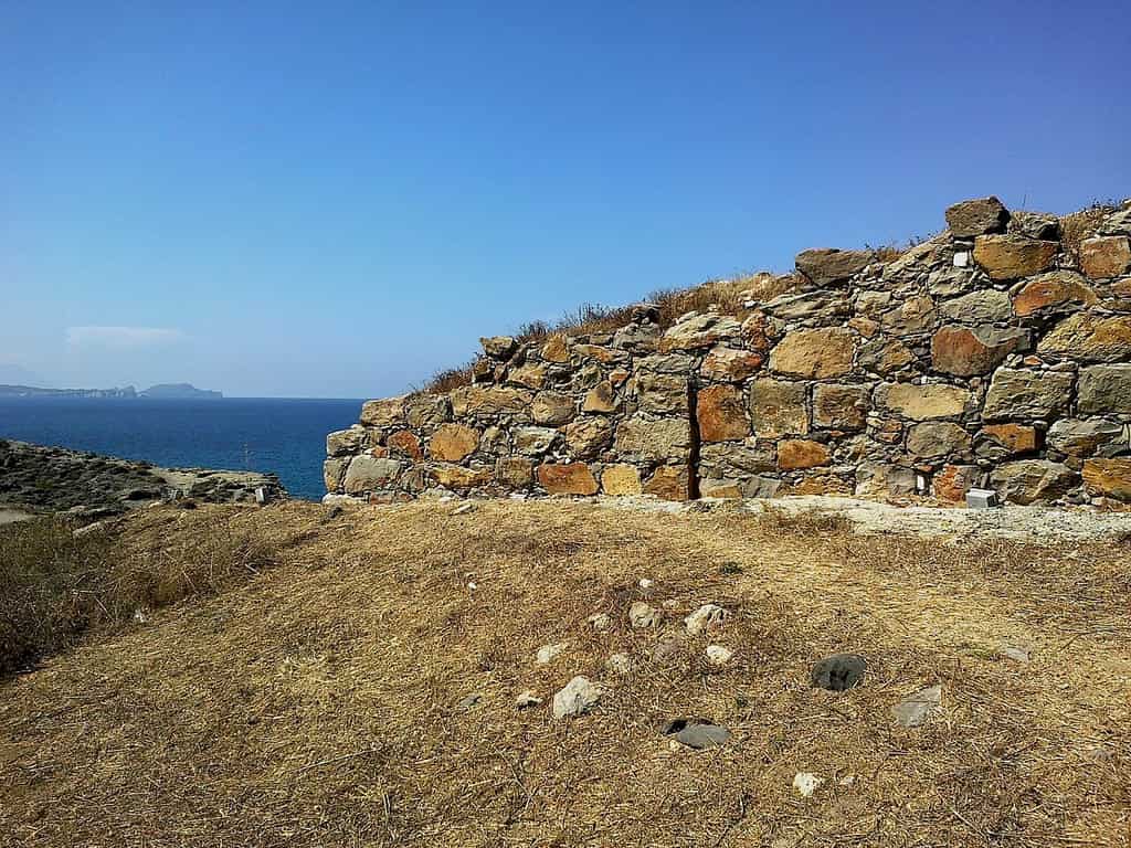 Φυλακωπή: ψηλό πέτρινο τείχος από μεγάλες πέτρες, με τη θάλασσα και ένα νησί πίσω του