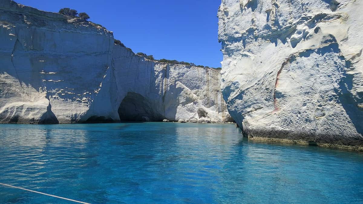 Κλέφτικο Μήλος: ψηλοί λευκοί βράχοι με θαλάσσιες σπηλιές πάνω από ήρεμο τιρκουάζ νερό