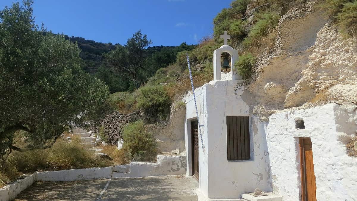 Λεωφορεία Μήλος: λευκό εκκλησάκι και πέτρινα σκαλιά κάτω από τις Κατακόμβες, κοντά στον δρόμο προς την Τρυπητή