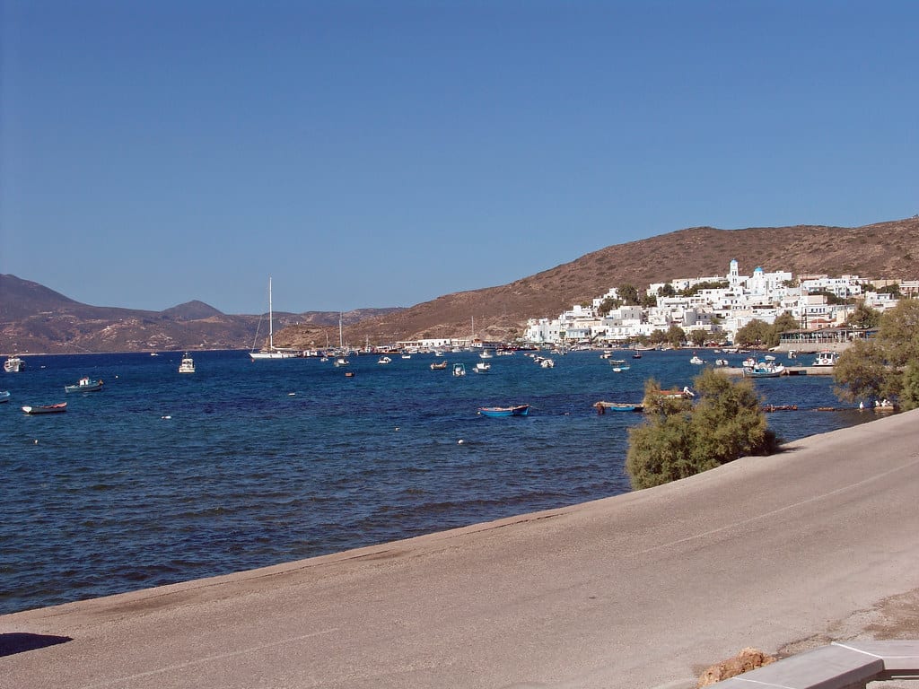 Μήλος με παιδιά: ο Αδάμαντας με λευκά σπίτια πάνω από τον κόλπο και βάρκες αγκυροβολημένες