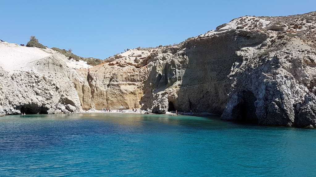 Τσιγκράδο: λευκοί και γκρι γκρεμοί με σπηλιές πάνω από γαλάζια θάλασσα, όπως φαίνονται από σκάφος